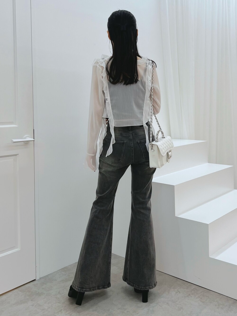 ブラック系のデニムパンツ、ブラック系のキャミソール、ホワイト系のカーディガン/ボレロを着用したレディースの秋コーディネートの3枚目の写真