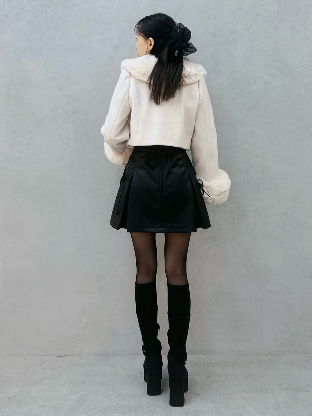 ブラック系のスカート、ホワイト系のその他アウター、ブラック系のブーツを着用したレディースの秋コーディネートの4枚目の写真