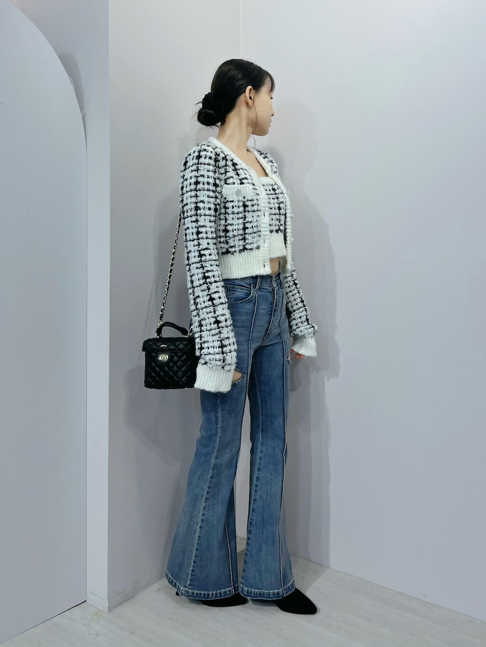 ブルー系のデニムパンツ、ホワイト系のニット/セーター、ブラック系のブーツを着用したレディースの秋コーディネートの2枚目の写真