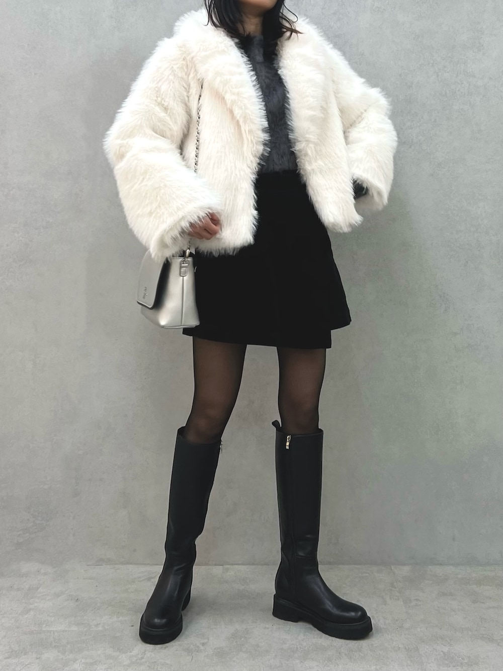 ホワイト系のその他アウター、グレー系のニット/セーター、シルバー系のショルダーバッグを着用したレディースの冬コーディネートの2枚目の写真