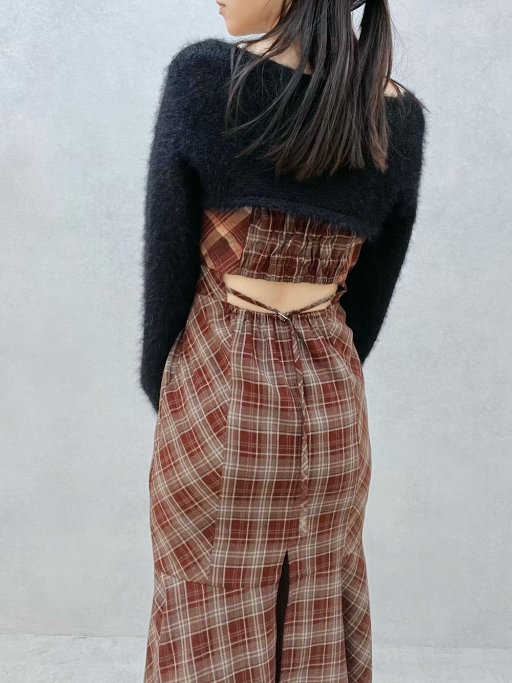 レッド系のワンピース、ブラック系のニット/セーター、ブラック系のブーツを着用したレディースの秋コーディネートの7枚目の写真