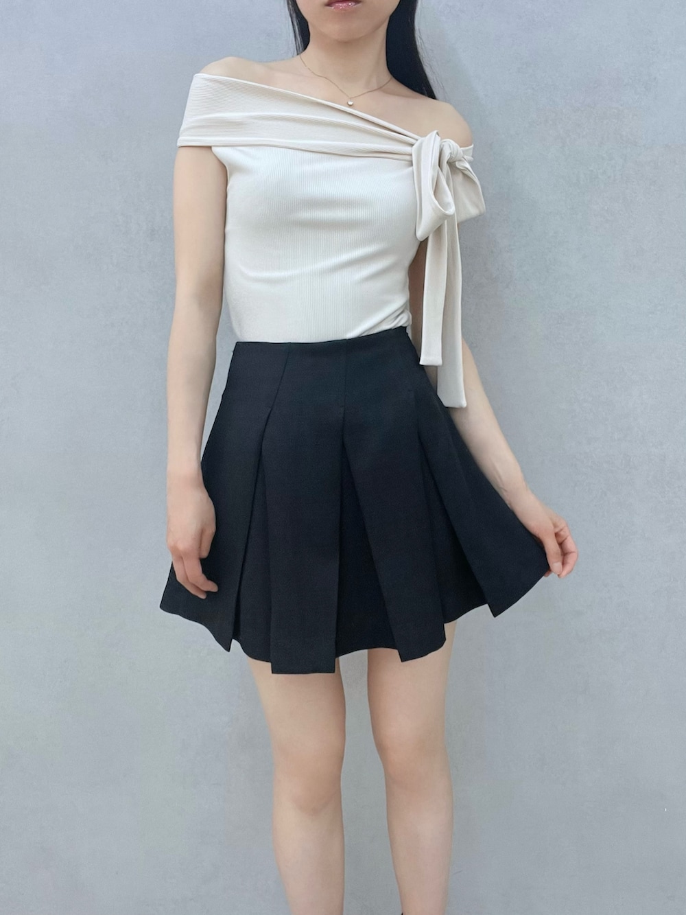 ブラック系のスカート、ホワイト系のTシャツ/カットソー、ブラック系のサンダルを着用したレディースの春コーディネートの6枚目の写真