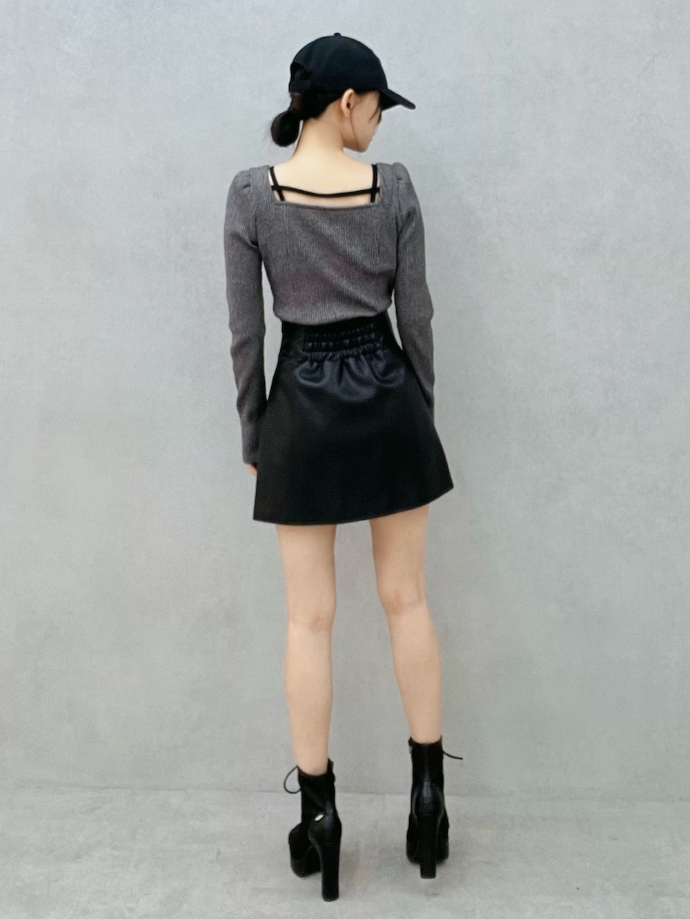 グレー系のTシャツ/カットソー、ブラック系のスカート、ブラック系のブーツを着用したレディースの冬コーディネートの3枚目の写真