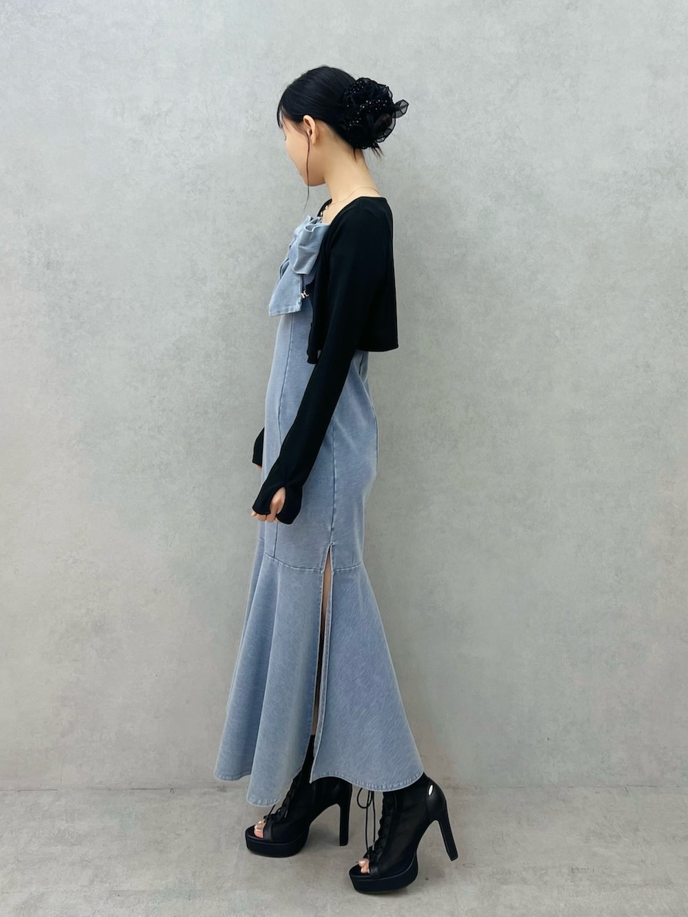 ブルー系のワンピース、ブラック系のTシャツ/カットソー、ブラック系のブーツを着用したレディースの春コーディネートの2枚目の写真