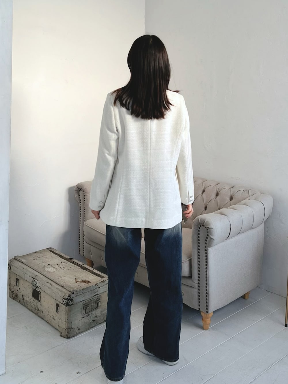 ホワイト系のテーラードジャケット、ブルー系のデニムパンツを着用したレディースの春コーディネートの3枚目の写真