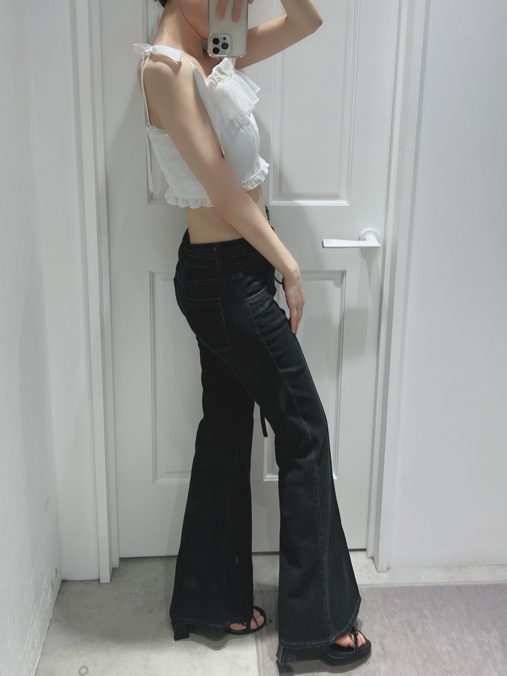 ブラック系のデニムパンツ、ブラック系のサンダル、ホワイト系のキャミソールを着用したレディースの春コーディネートの2枚目の写真