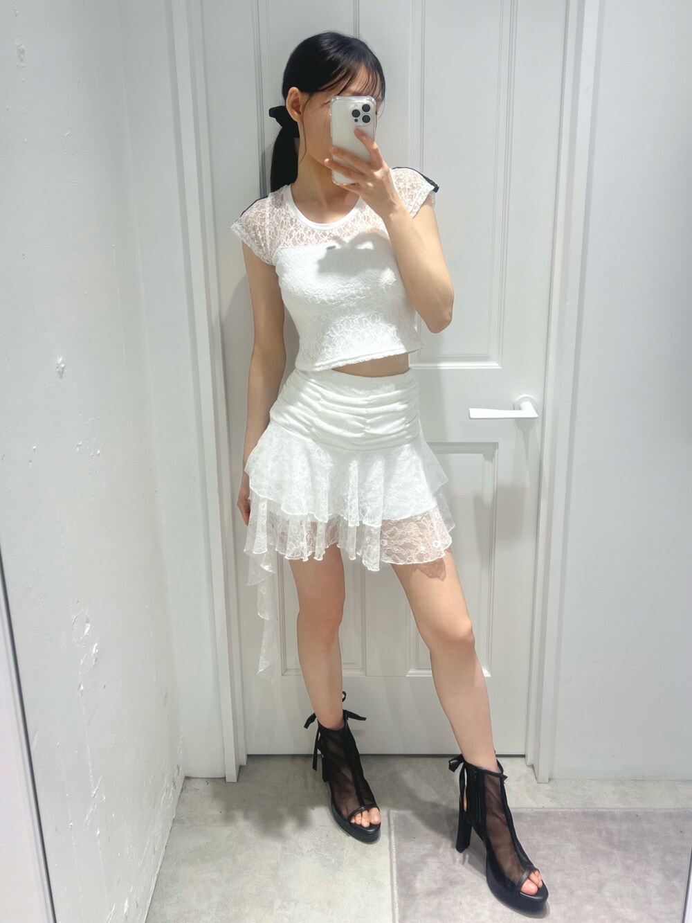 ホワイト系のスカート、ホワイト系のTシャツ/カットソー、ブラック系のサンダルを着用したレディースの春コーディネートの2枚目の写真