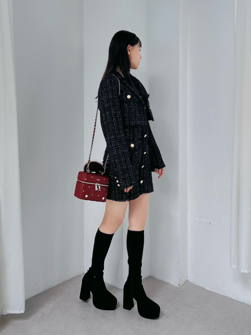 ブラック系のワンピース、レッド系のハンドバッグ、ブラック系のブーツを着用したレディースの夏コーディネートの4枚目の写真