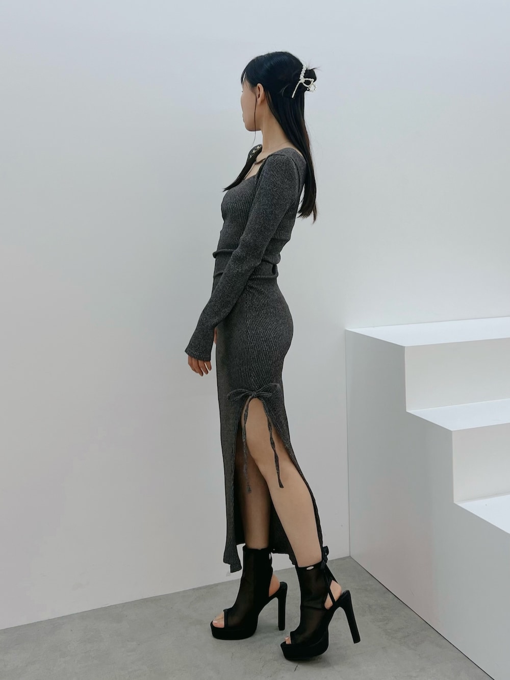 ブラック系のサンダル、グレー系のワンピース、ブラック系のハンドバッグを着用したレディースの春コーディネートの2枚目の写真