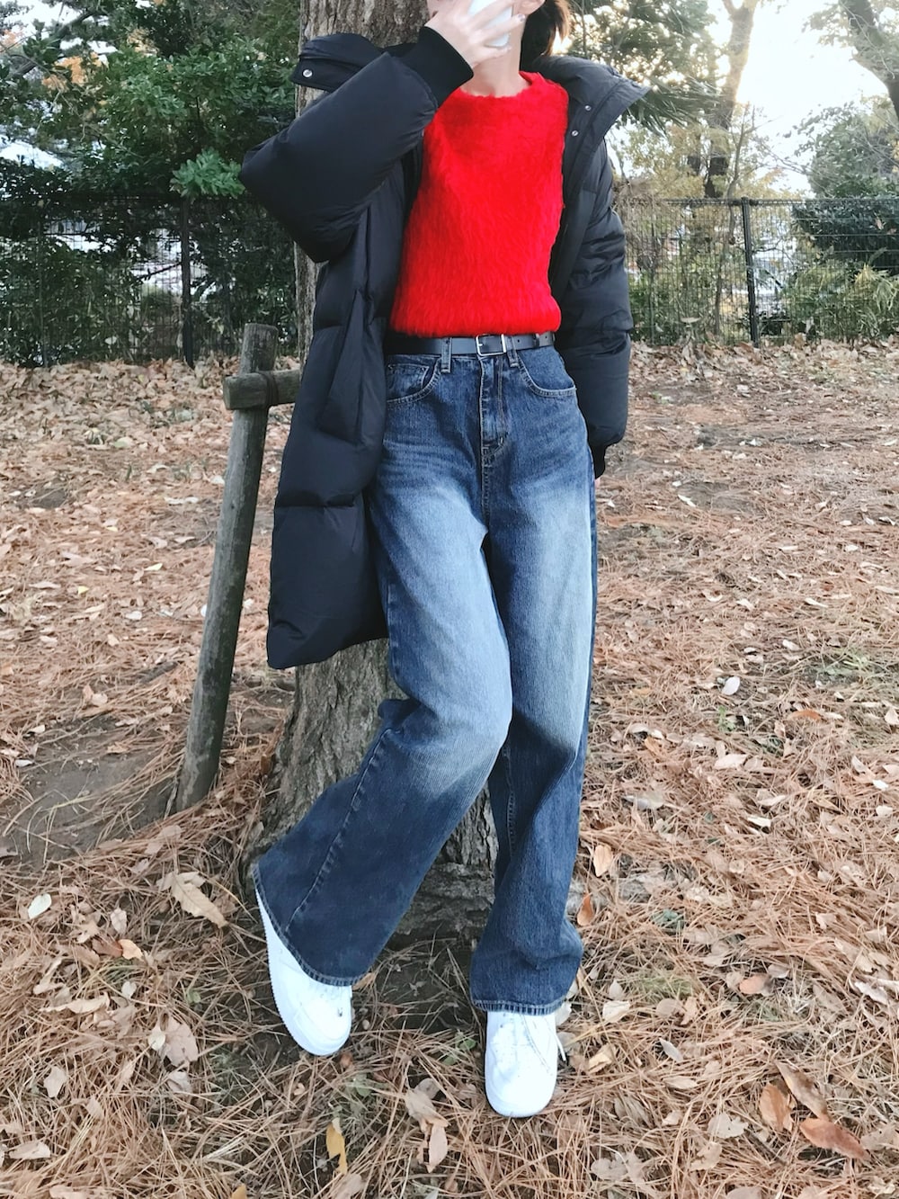 レッド系のニット/セーター、ブルー系のデニムパンツを着用したレディースの冬コーディネートの3枚目の写真