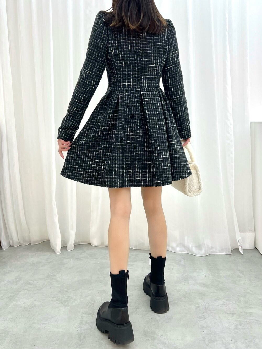 ブラック系のワンピース、ホワイト系のハンドバッグを着用したレディースの冬コーディネートの3枚目の写真