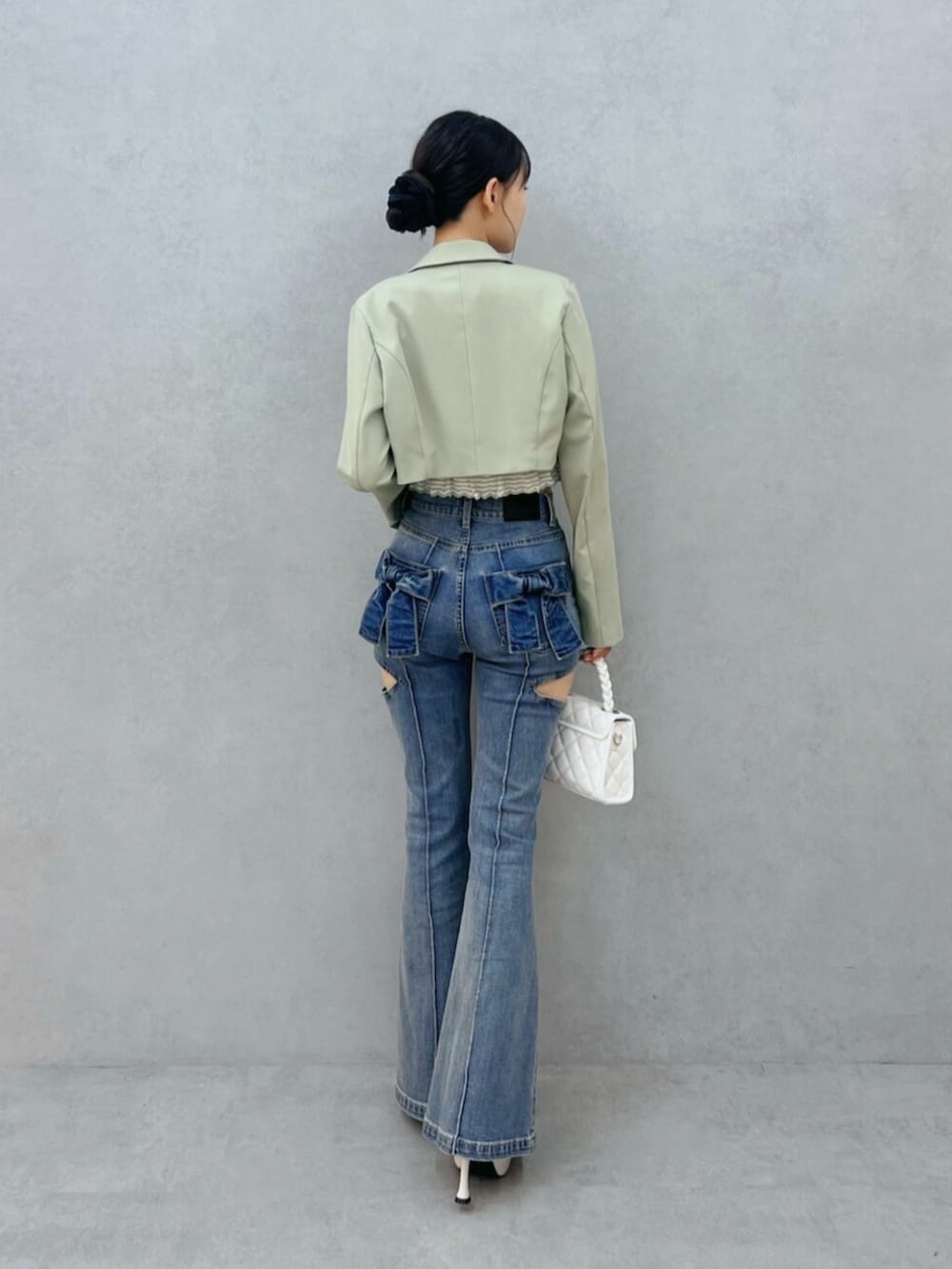 ブルー系のデニムパンツ、ホワイト系のハンドバッグ、ホワイト系のブーツを着用したレディースの秋コーディネートの3枚目の写真