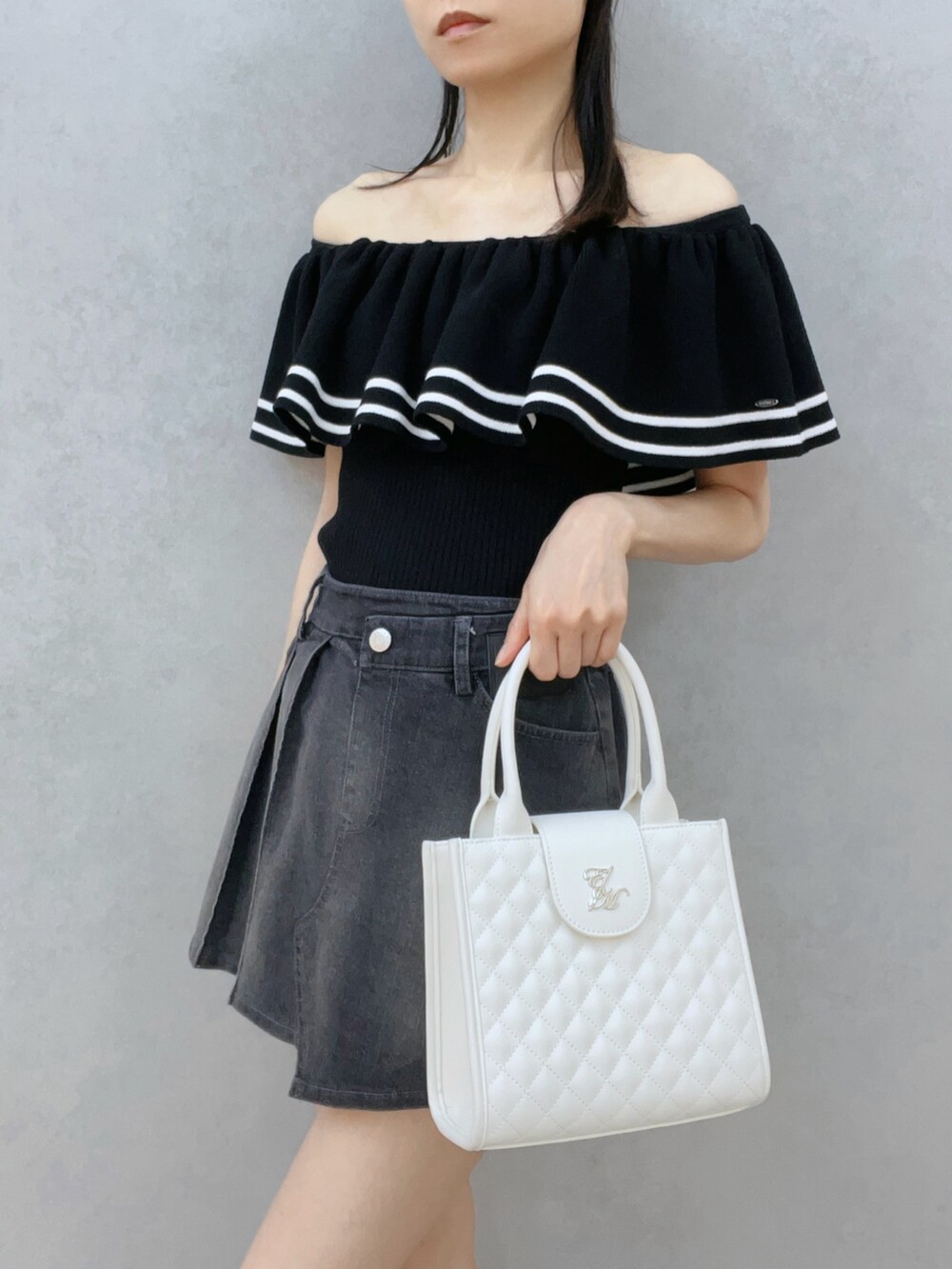 ブラック系のデニムスカート、ブラック系のサンダル、ホワイト系のハンドバッグを着用したレディースの夏コーディネートの6枚目の写真