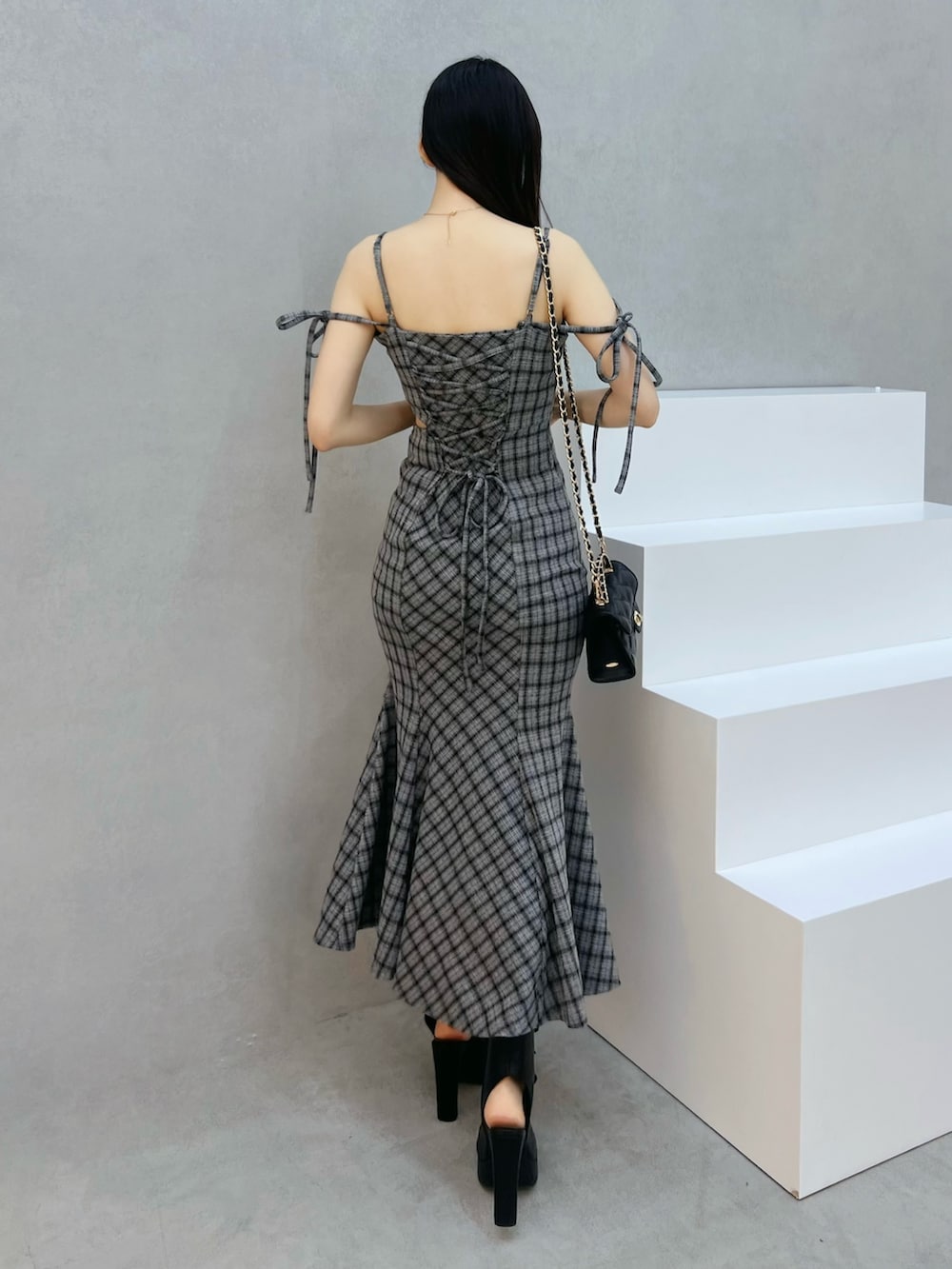 グレー系のワンピース、ブラック系のハンドバッグ、ブラック系のサンダルを着用したレディースの夏コーディネートの3枚目の写真