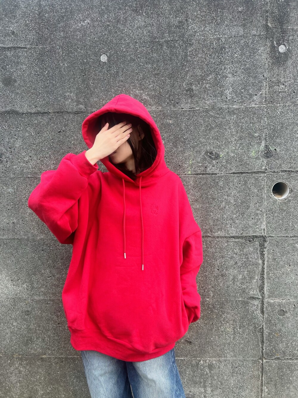 レッド系のパーカー、ブルー系のデニムパンツを着用したレディースの冬コーディネートの5枚目の写真