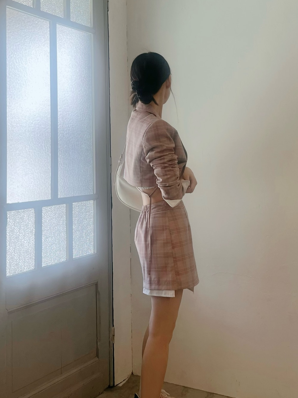 ピンク系のスカート、ホワイト系のショルダーバッグ、ピンク系のテーラードジャケットを着用したレディースの春コーディネートの4枚目の写真