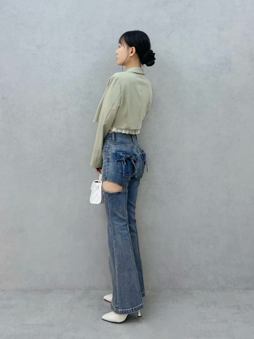 ブルー系のデニムパンツ、ホワイト系のハンドバッグ、ホワイト系のブーツを着用したレディースの秋コーディネートの4枚目の写真