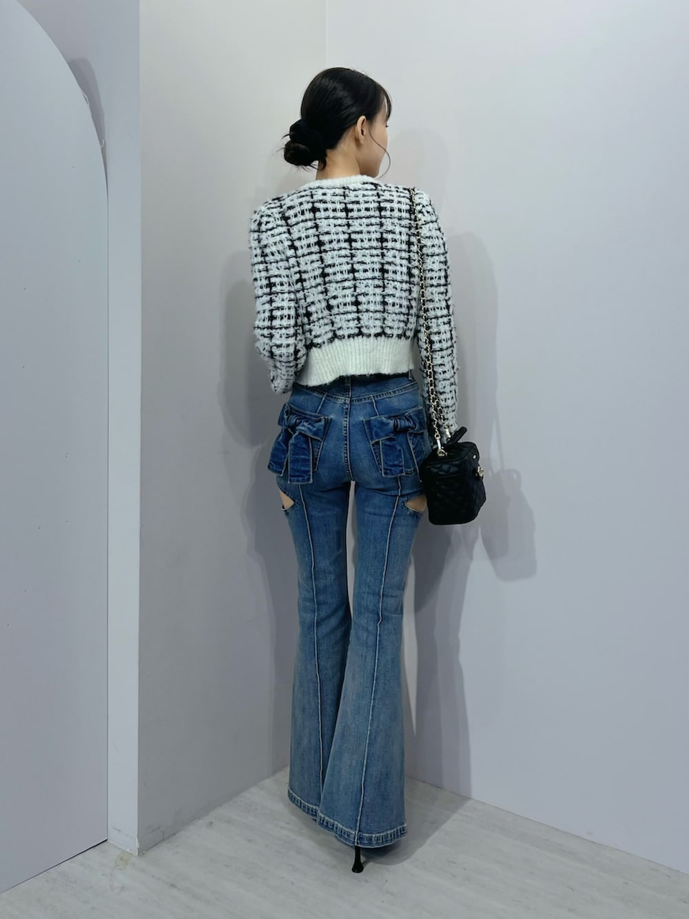 ブルー系のデニムパンツ、ホワイト系のニット/セーター、ブラック系のブーツを着用したレディースの秋コーディネートの3枚目の写真