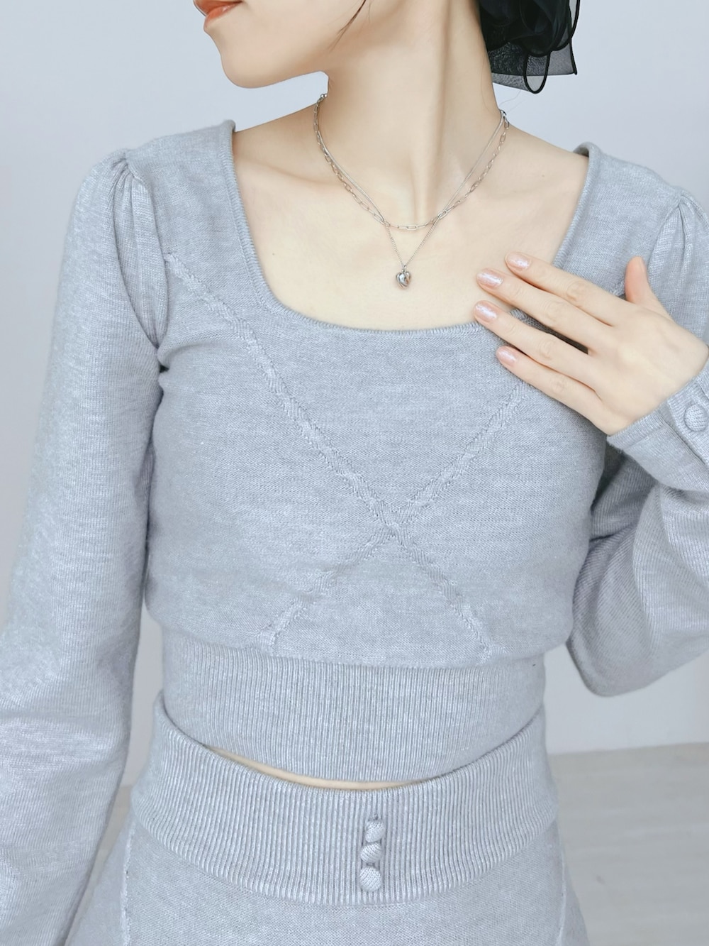 ホワイト系のショルダーバッグ、グレー系のニット/セーター、グレー系のスカートを着用したレディースの秋コーディネートの5枚目の写真