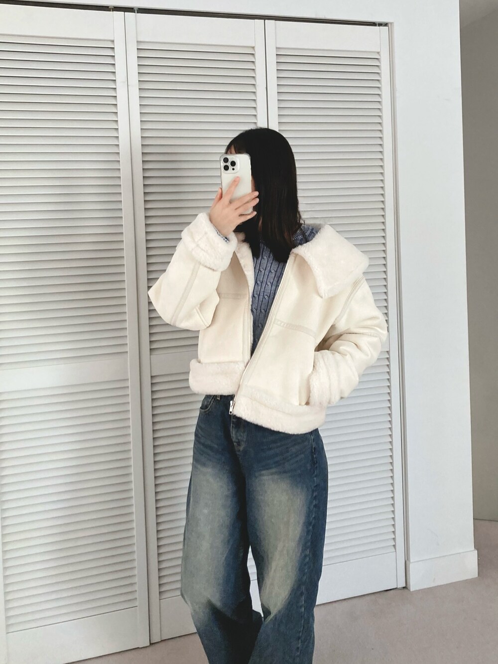 ホワイト系のブルゾン、ブルー系のデニムパンツを着用したレディースの冬コーディネートの3枚目の写真