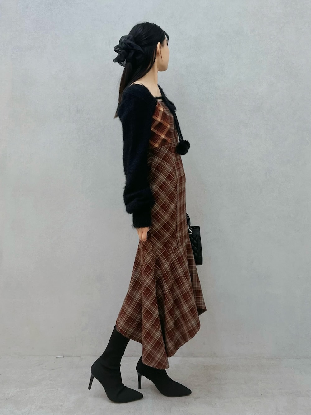 レッド系のワンピース、ブラック系のニット/セーター、ブラック系のブーツを着用したレディースの秋コーディネートの3枚目の写真