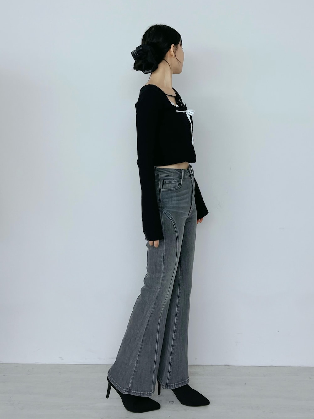 ブラック系のデニムパンツ、ブラック系のニット/セーター、ブラック系のブーツを着用したレディースの秋コーディネートの2枚目の写真