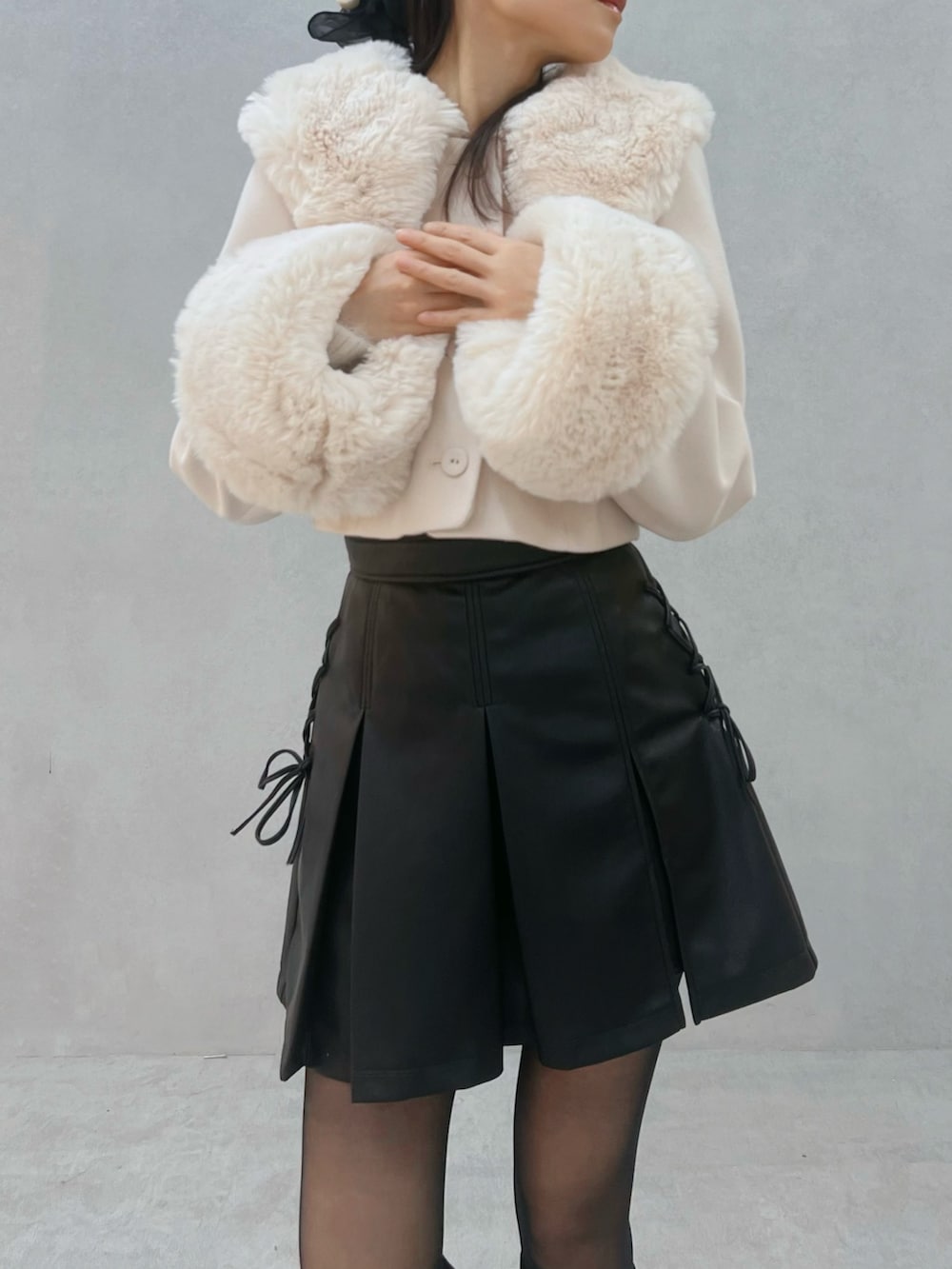 ブラック系のスカート、ホワイト系のその他アウター、ブラック系のブーツを着用したレディースの秋コーディネートの6枚目の写真