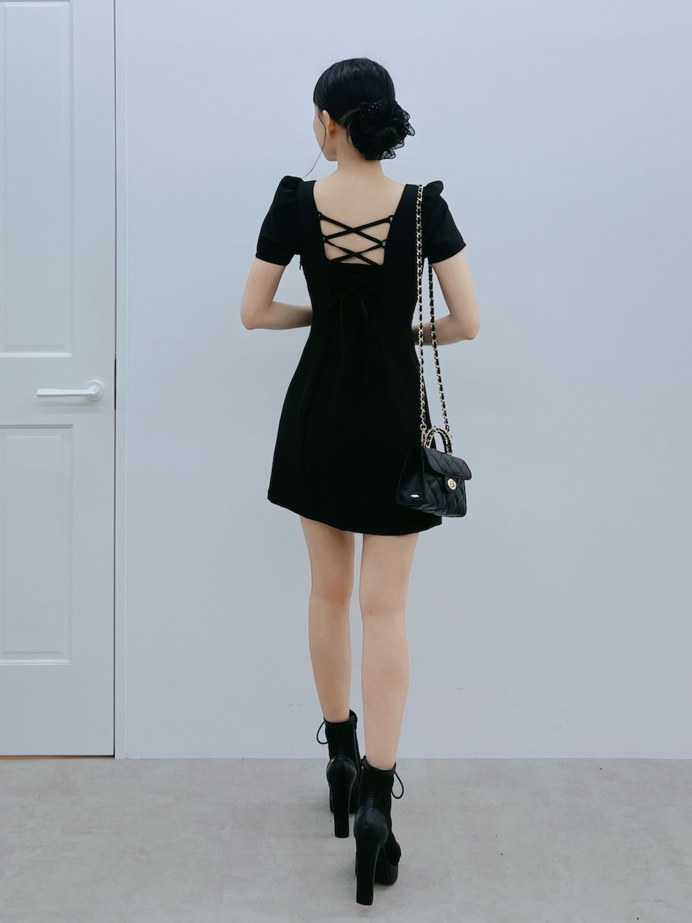 ブラック系のワンピース、ブラック系のブーツ、ブラック系のハンドバッグを着用したレディースの春コーディネートの3枚目の写真