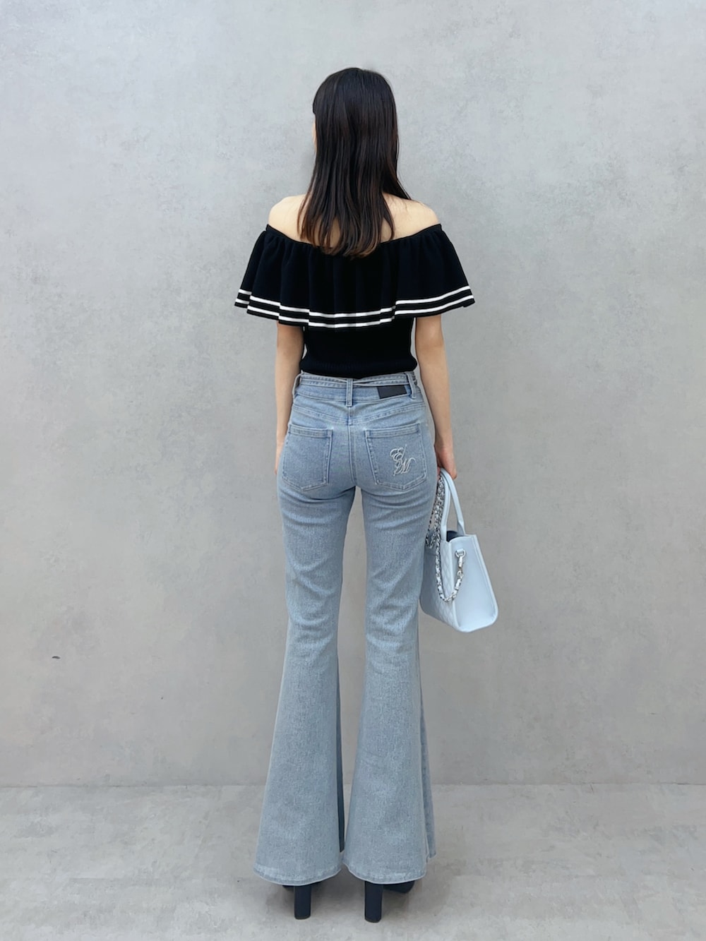 ブルー系のハンドバッグ、ブルー系のデニムパンツ、ブラック系のニット/セーターを着用したレディースの夏コーディネートの5枚目の写真