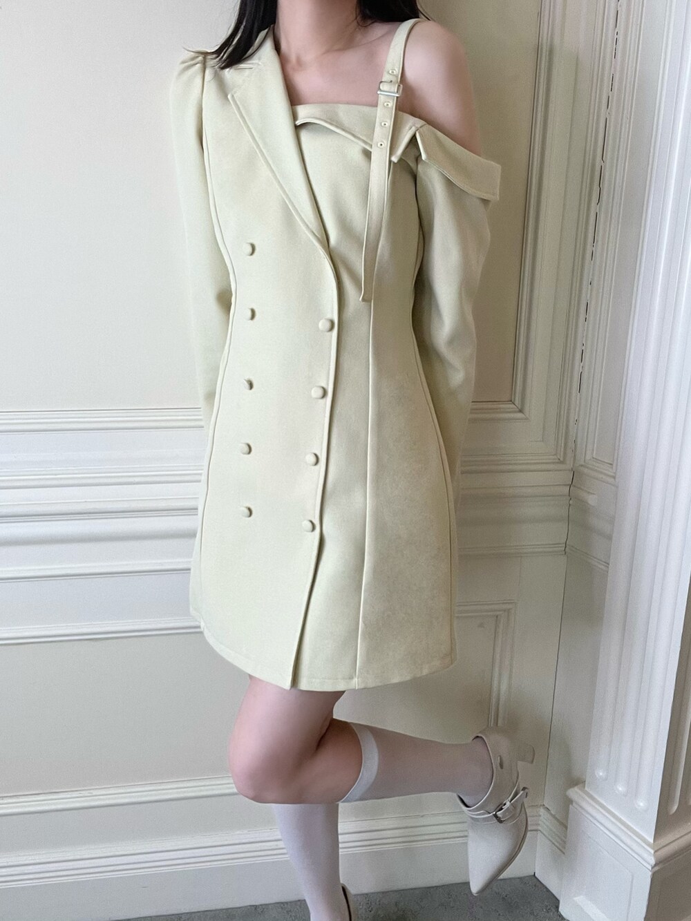 イエロー系のワンピース、ホワイト系のブーツを着用したレディースの冬コーディネートの2枚目の写真