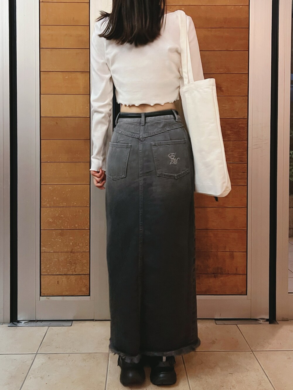 ブラック系のデニムスカート、ホワイト系のTシャツ/カットソーを着用したレディースの夏コーディネートの5枚目の写真