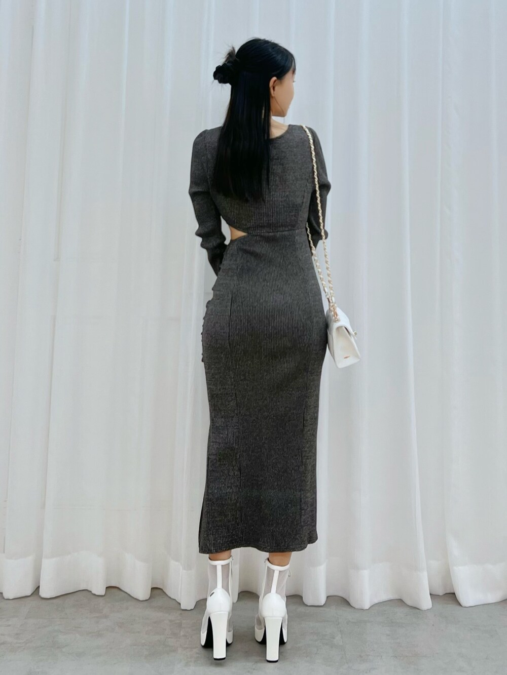 グレー系のワンピース、ホワイト系のブーツ、ホワイト系のハンドバッグを着用したレディースの冬コーディネートの3枚目の写真