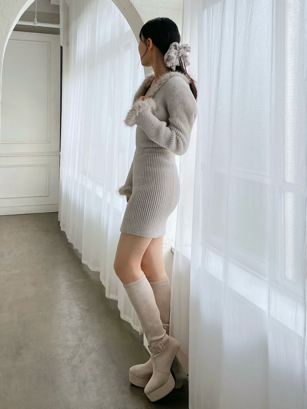 グレー系のワンピース、ホワイト系のブーツを着用したレディースの冬コーディネートの2枚目の写真