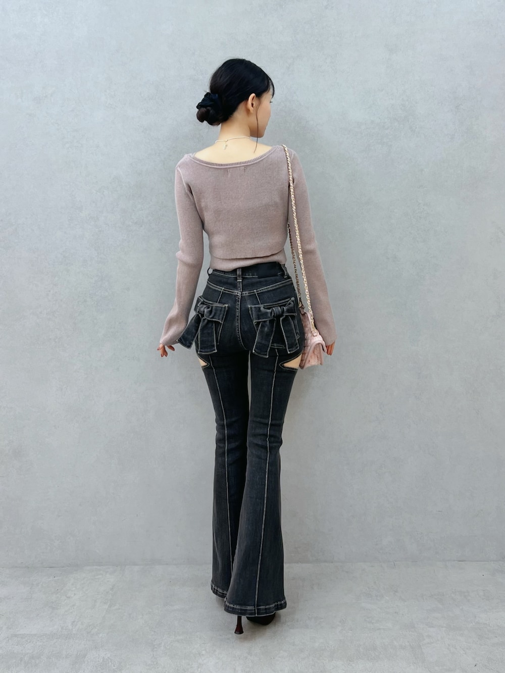 ブラック系のデニムパンツ、レッド系のブーツ、ベージュ系のニット/セーターを着用したレディースの夏コーディネートの3枚目の写真