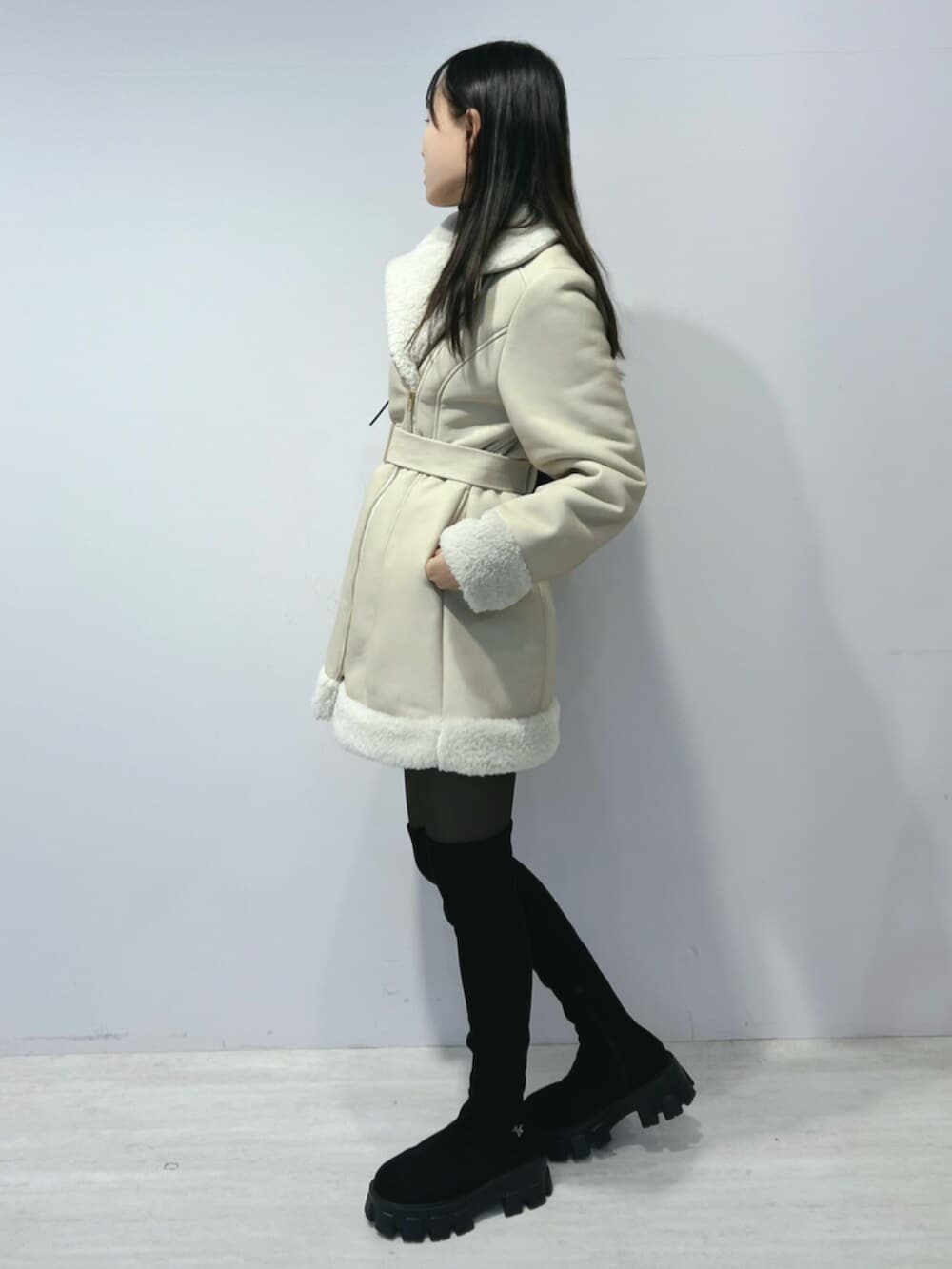 ブラック系のショルダーバッグ、ブラック系のブーツ、ベージュ系のムートンコートを着用したレディースの冬コーディネートの3枚目の写真