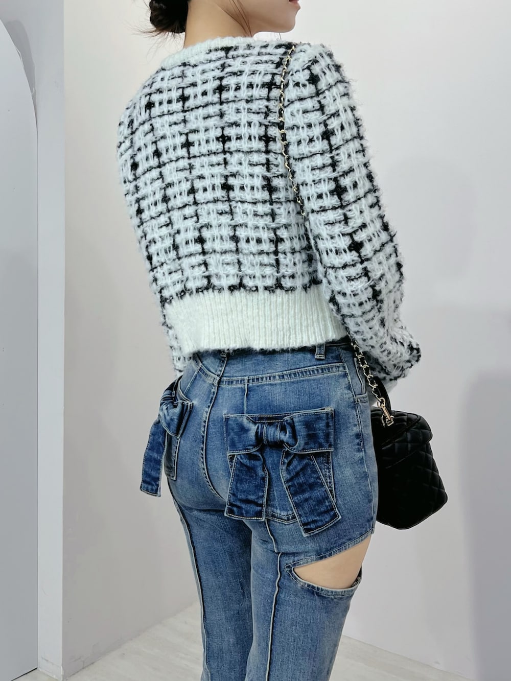 ブルー系のデニムパンツ、ホワイト系のニット/セーター、ブラック系のブーツを着用したレディースの秋コーディネートの5枚目の写真