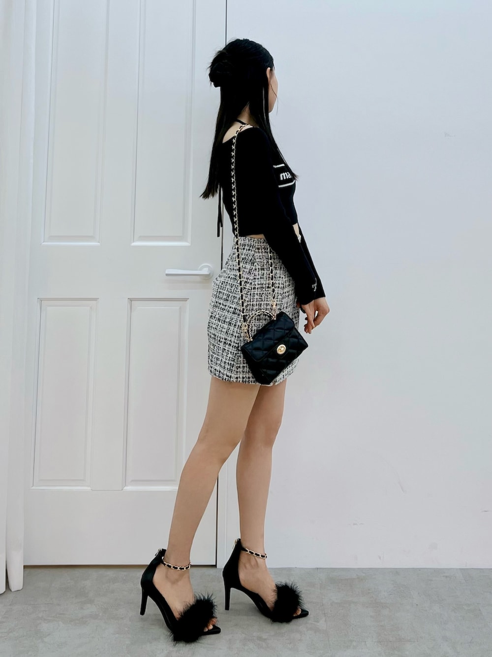 ブラック系のサンダル、ブラック系のハンドバッグ、ブラック系のスカートを着用したレディースの冬コーディネートの2枚目の写真