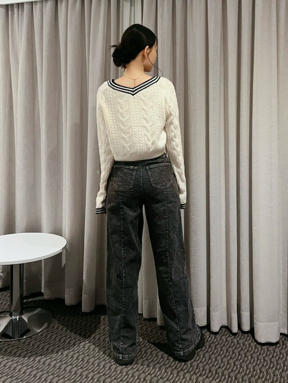 ホワイト系のニット/セーター、ブラック系のデニムパンツ、ゴールド系のネックレスを着用したレディースの秋コーディネートの3枚目の写真