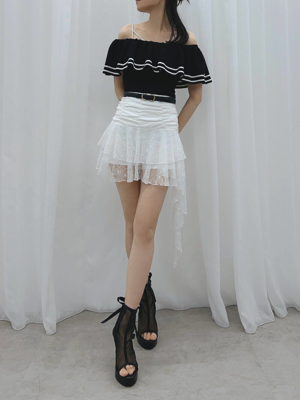 ブラック系のサンダル、ブラック系のニット/セーター、ホワイト系のスカートを着用したレディースの夏コーディネートの2枚目の写真