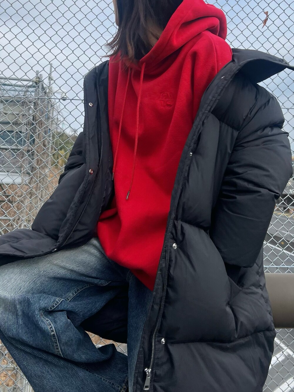 レッド系のパーカー、ブルー系のデニムパンツを着用したレディースの冬コーディネートの2枚目の写真