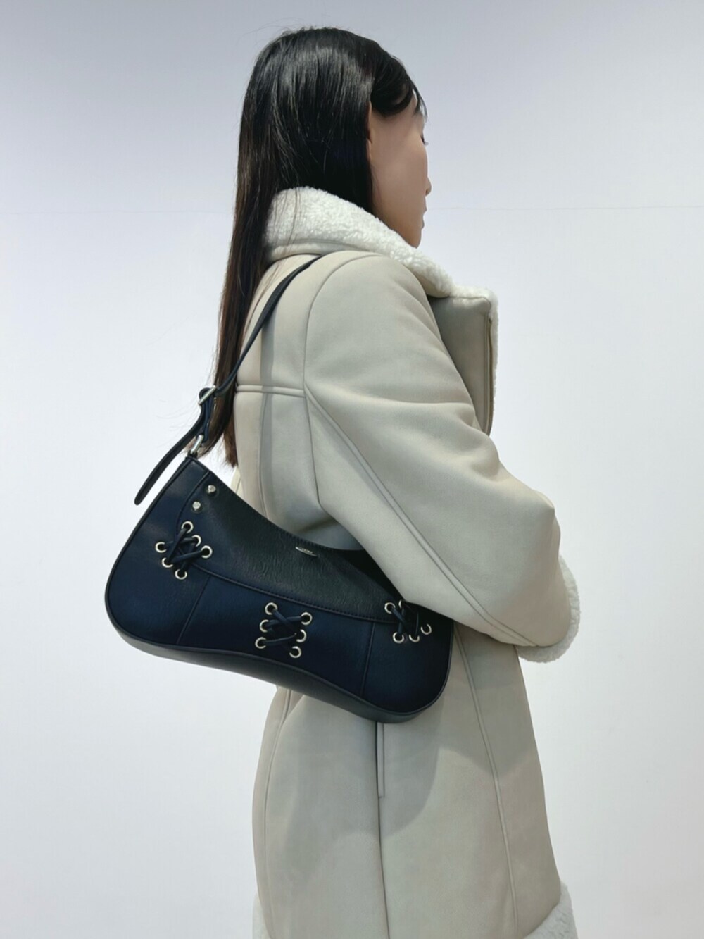 ブラック系のショルダーバッグ、ブラック系のブーツ、ベージュ系のムートンコートを着用したレディースの冬コーディネートの5枚目の写真