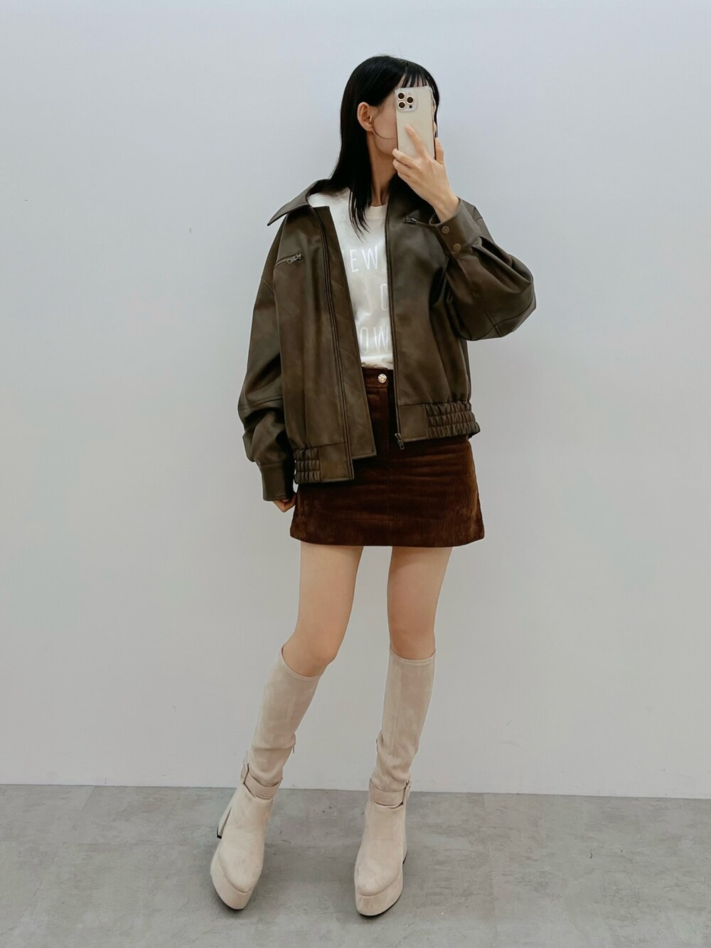 ブラウン系のブルゾン、ホワイト系のブーツを着用したレディースの秋コーディネートの2枚目の写真