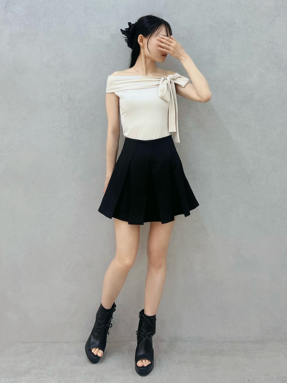 ブラック系のスカート、ホワイト系のTシャツ/カットソー、ブラック系のサンダルを着用したレディースの春コーディネートの4枚目の写真