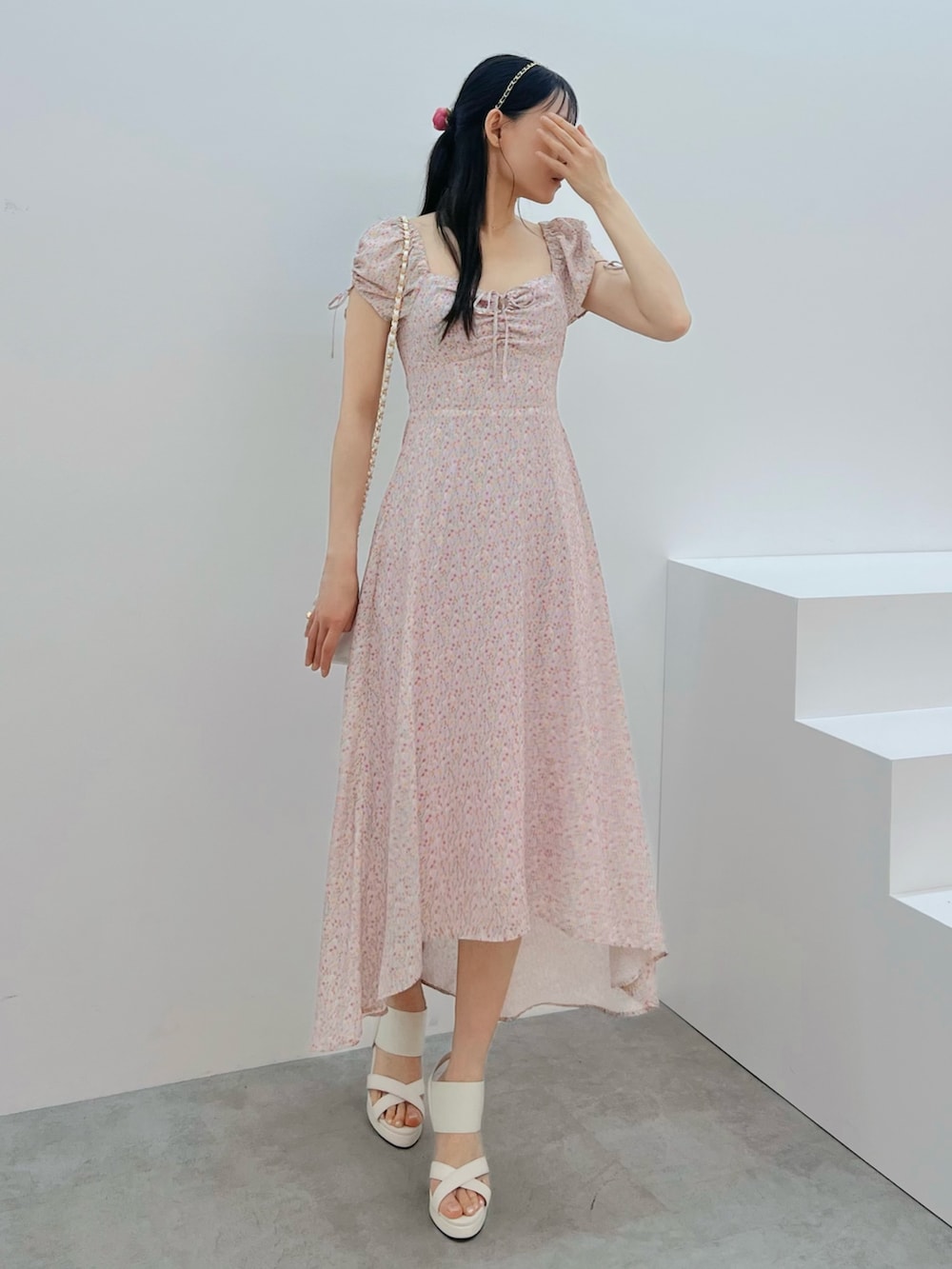 ピンク系のワンピース、ホワイト系のハンドバッグ、ホワイト系のサンダルを着用したレディースの春コーディネートの4枚目の写真