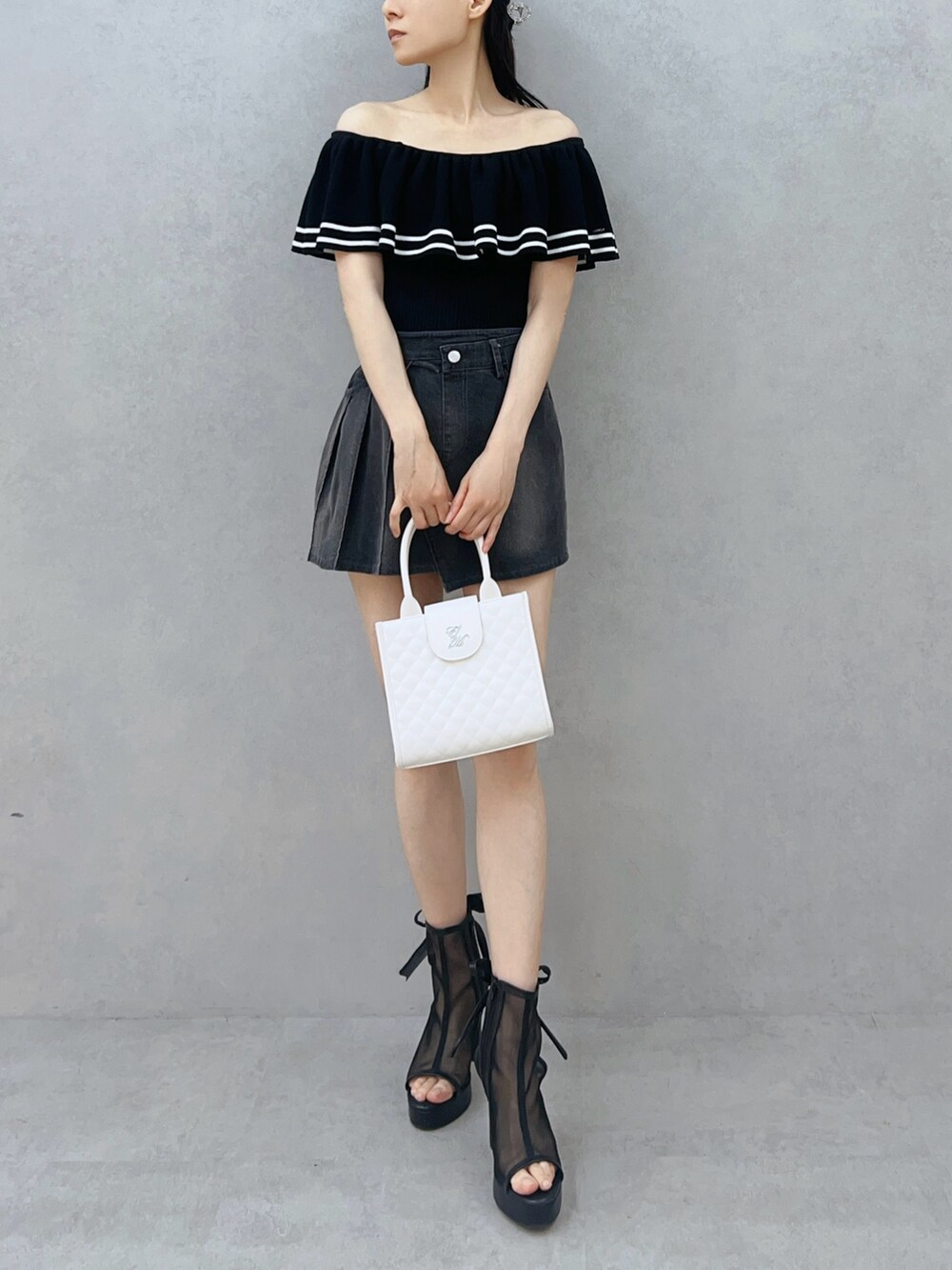 ブラック系のデニムスカート、ブラック系のサンダル、ホワイト系のハンドバッグを着用したレディースの夏コーディネートの2枚目の写真