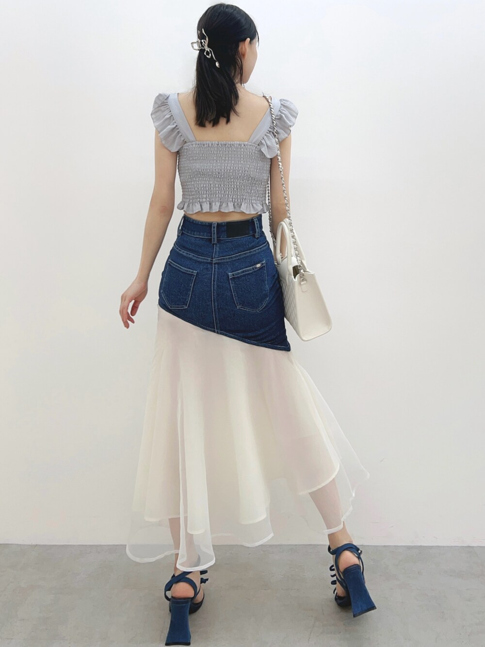 ブルー系のデニムスカート、ホワイト系のハンドバッグ、グレー系のシャツ/ブラウスを着用したレディースの春コーディネートの6枚目の写真