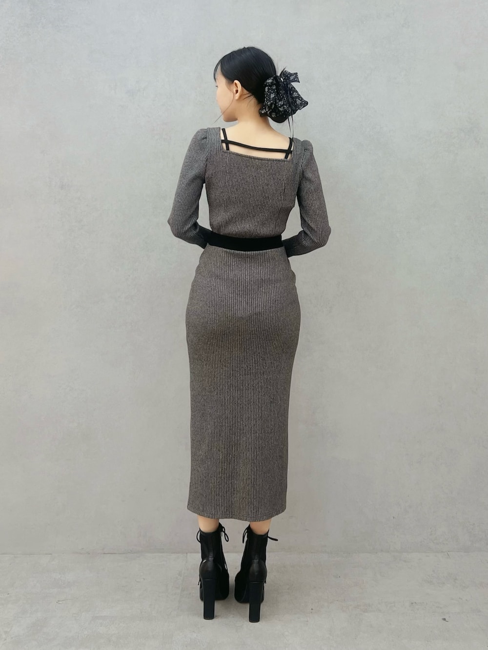 グレー系のスカート、グレー系のTシャツ/カットソー、ブラック系のブーツを着用したレディースの冬コーディネートの3枚目の写真