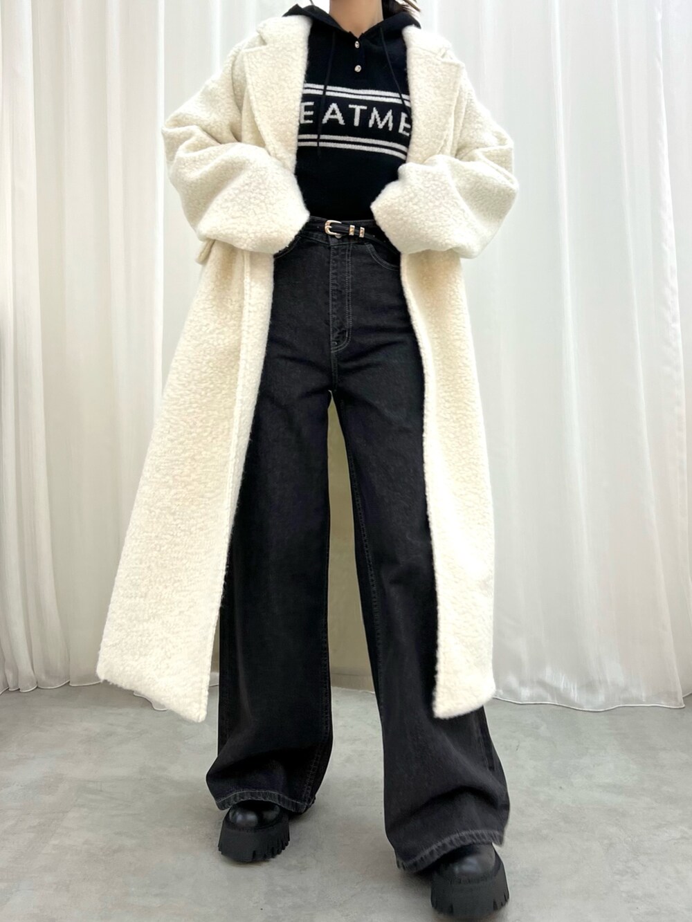 ブラック系のデニムパンツ、ホワイト系のチェスターコート、ブラック系のワンピースを着用したレディースの冬コーディネートの2枚目の写真