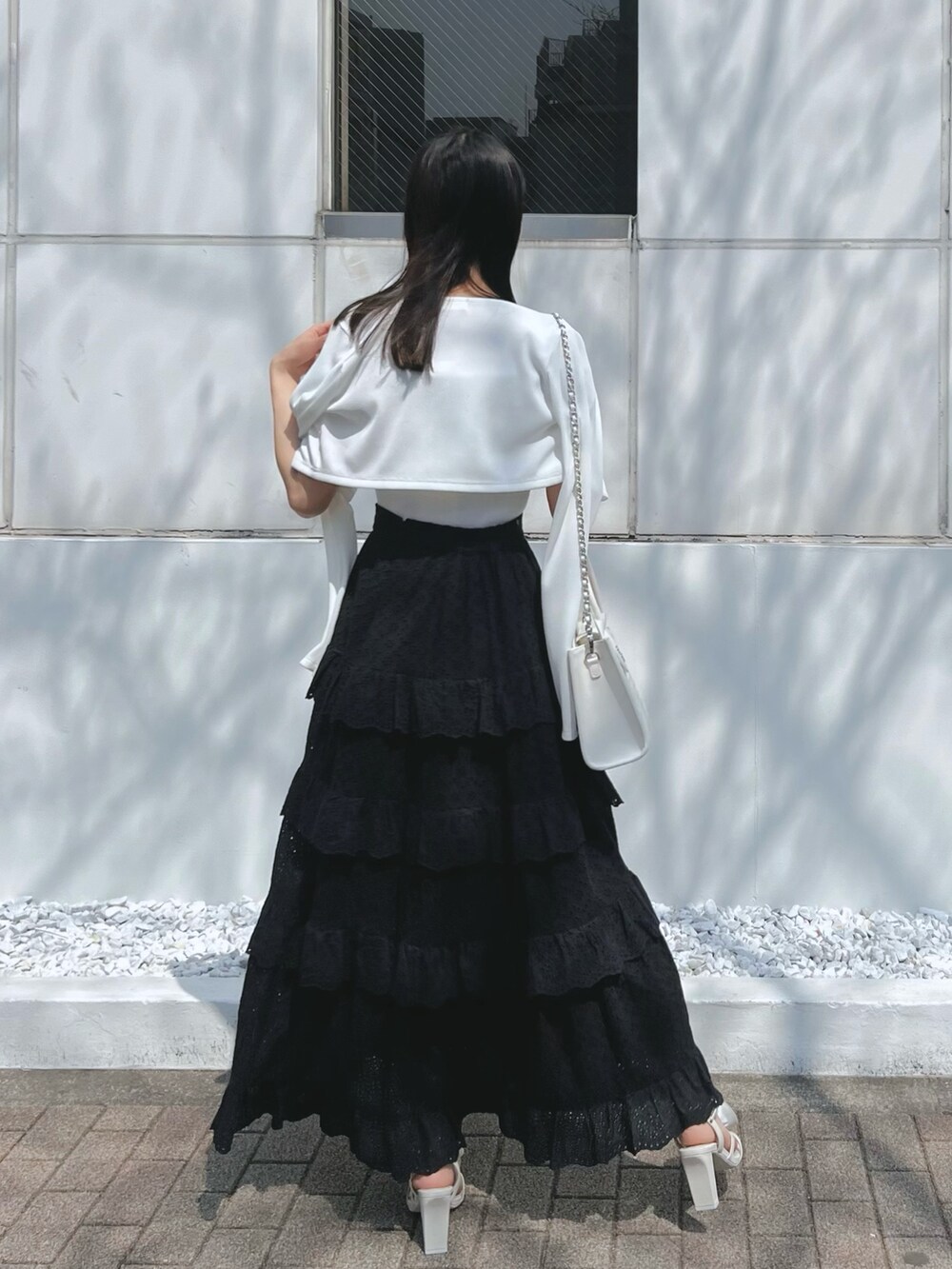 ブラック系のスカート、ホワイト系のワンピース、ホワイト系のサンダルを着用したレディースの春コーディネートの4枚目の写真