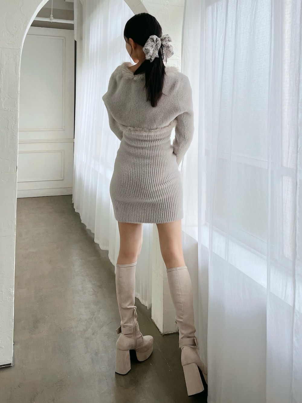 グレー系のワンピース、ホワイト系のブーツを着用したレディースの冬コーディネートの3枚目の写真